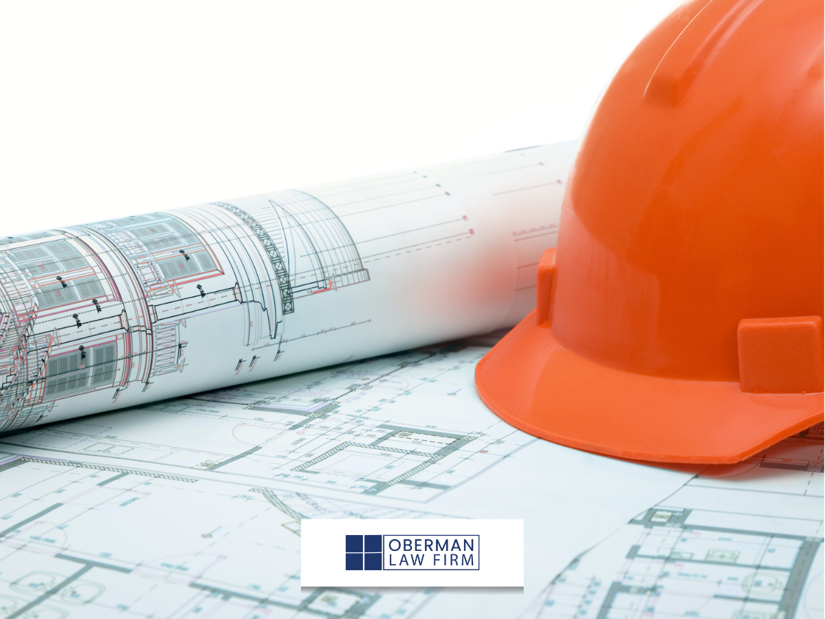 orange construction hat sitting on top of blue prints and plans