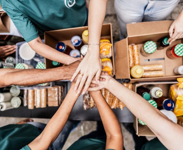 Close-up of volunteers with hands stacked during donation event outdoors