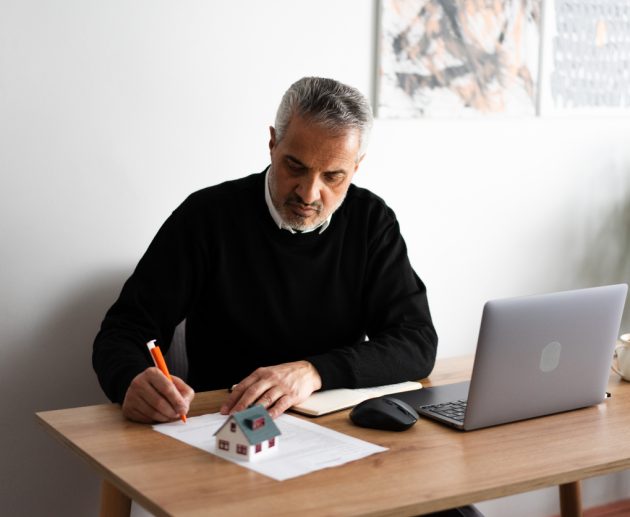 Mature real estate agent signing a contract for a new house purchase in his office