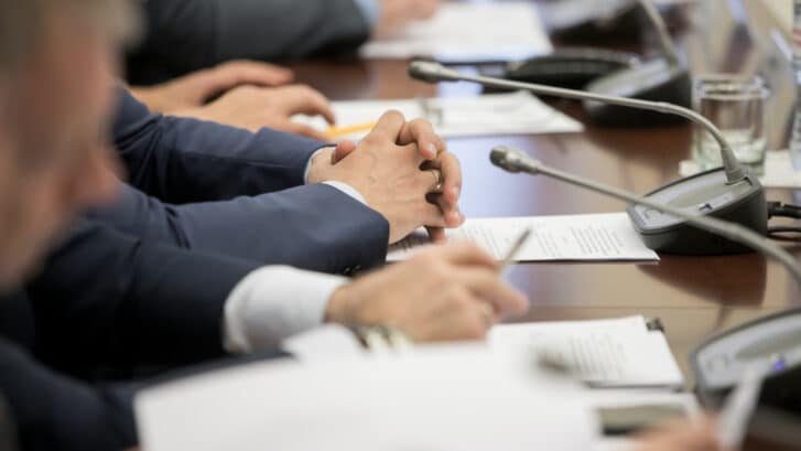 One,Of,Politician,Sitting,By,Table,With,His,Hands,Over