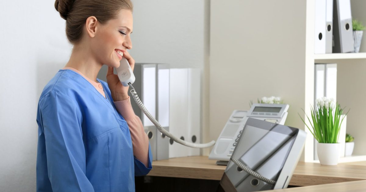 Young female receptionist talking on the phone in hospital