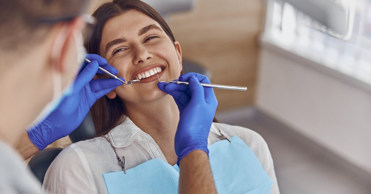 Professional doctor is checking woman's teeth in light modern dental clinic
