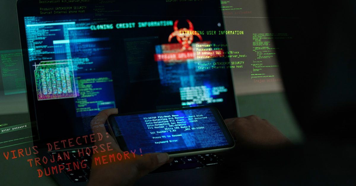 Cybersecurity, fraud and hands on a laptop and phone while programming or hacking a website. Scam, cyber attack and man hacker coding on a computer to steal information or data technology in the dark