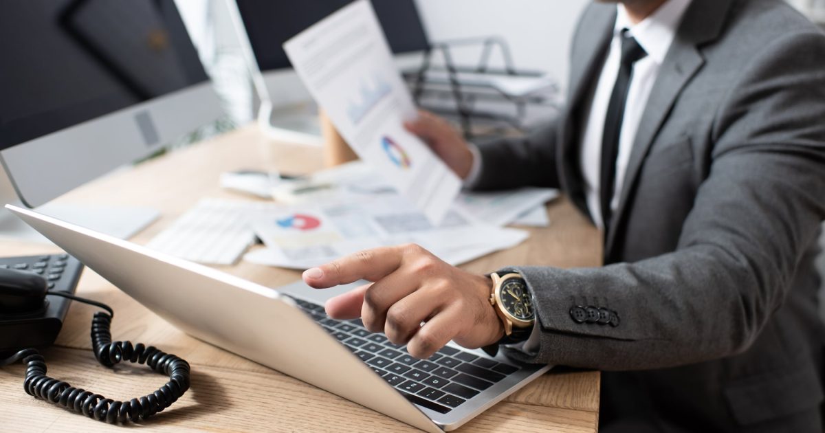 man at desk with computer and paperwork