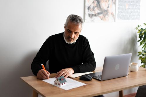 Mature real estate agent signing a contract for a new house purchase in his office