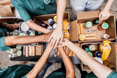 Close-up of volunteers with hands stacked during donation event outdoors